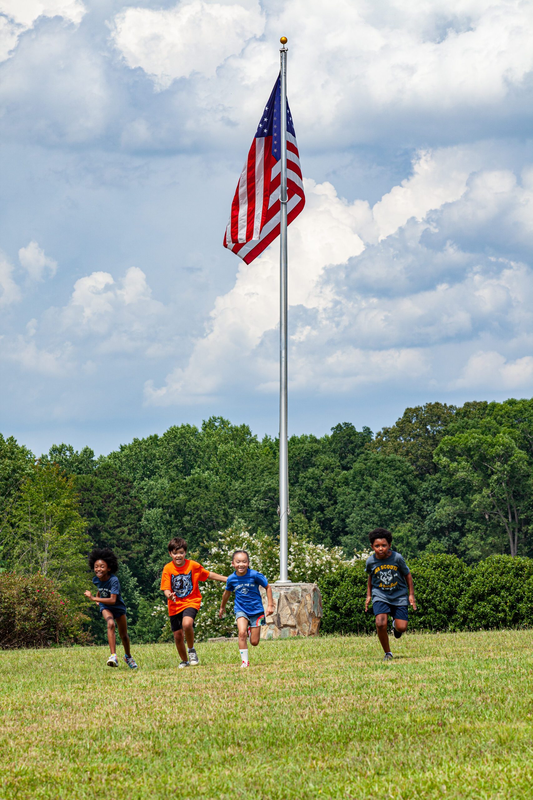 Running in a field; American flag in background; playing tag; racing